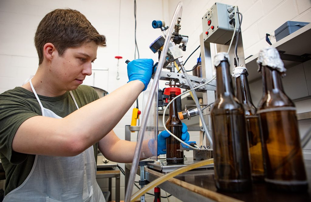 Die Abfüllanlage hilft dabei, das Bier unter Druck in die Flaschen zu geben. Niklas Hoffmann hat sie gut im Griff. Foto: Universität Bielefeld / Mike-Dennis Müller