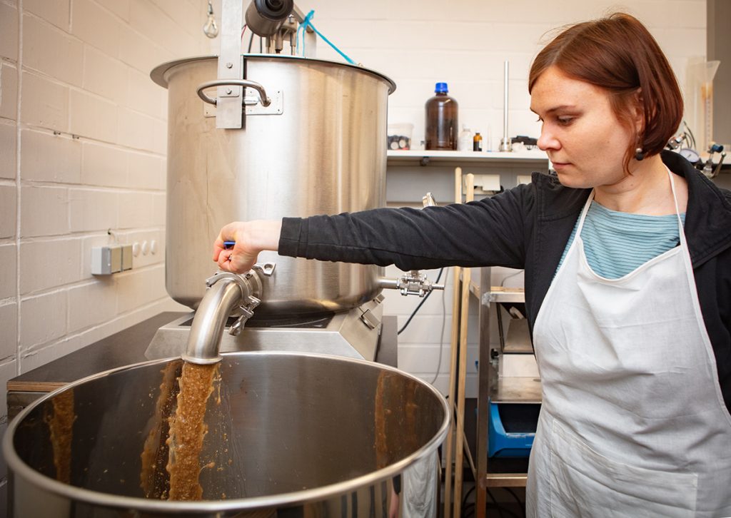 Abmaischen nennen die Profis, wenn das gekochte Malz abgelassen wird. Claudia Curdt bedient den Hahn. Foto: Universität Bielefeld / Mike-Dennis Müller