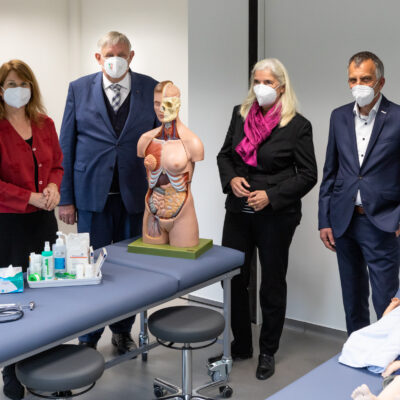 Rektor Sagerer (r.) und Gründungsdekanin Hornberg (l.) führen Minister Laumann und Ministerin Pfeiffer-Poensgen durch einen Raum im „Skills Lab“ im Gebäude R.1 an der Morgenbreede. In diesem Bereich trainieren die Studierenden praktische ärztliche Fertigkeiten unter kontrollierten Bedingungen.