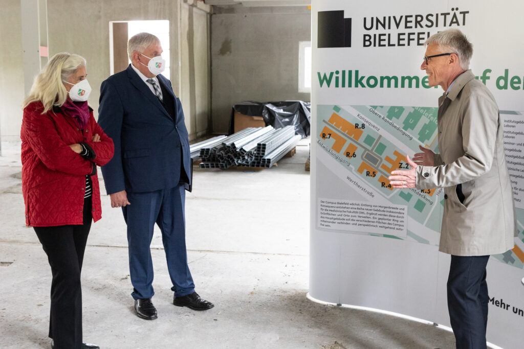 Kanzler Dr. Stephan Becker (r.) präsentiert Wissenschaftsministerin Isabel Pfeiffer-Poensgen und Gesundheitsminister Karl-Josef Laumann den Stand der Baumaßnahmen auf dem Campus Süd.