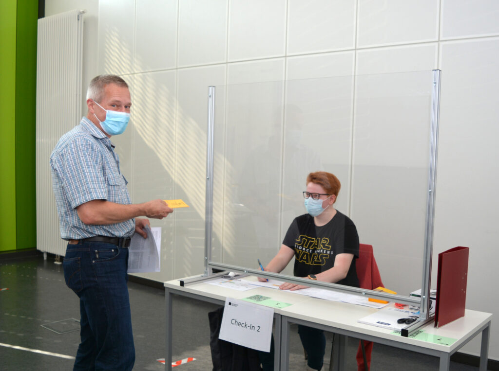 Dr. Joe Max Risse aus der Technischen Fakultät bei der Registrierung im Check-In durch die Auszubildende Alyssa Kruse.