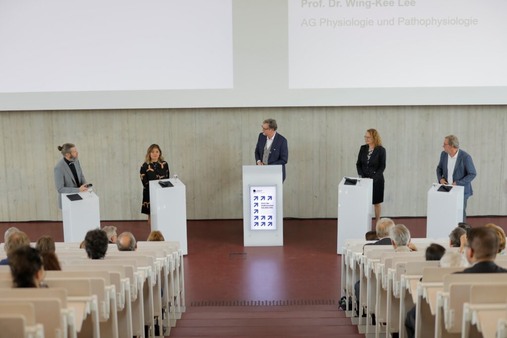 Diskussionsrunde mit Prof. Dr. Björn Spittau, AG Anatomie und Zellbiologie, Prof‘in Dr. Wing-Kee Lee, AG Physiologie und Pathophysiologie Prof‘in Dr. Christiane Muth, AG Allgemein- und Familienmedizin und Prof. Dr. Martin Driessen, Klinik für Psychiatrie und Psychotherapie. Ev. Klinikum Bethel (v.l.) moderiert von Dr. Eckart von Hirschhausen (mitte). Foto: Universität Bielefeld/S.Sättele