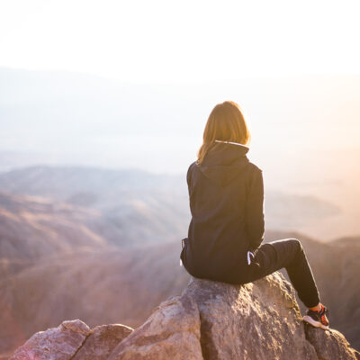 Woman, sitting in front of landscape